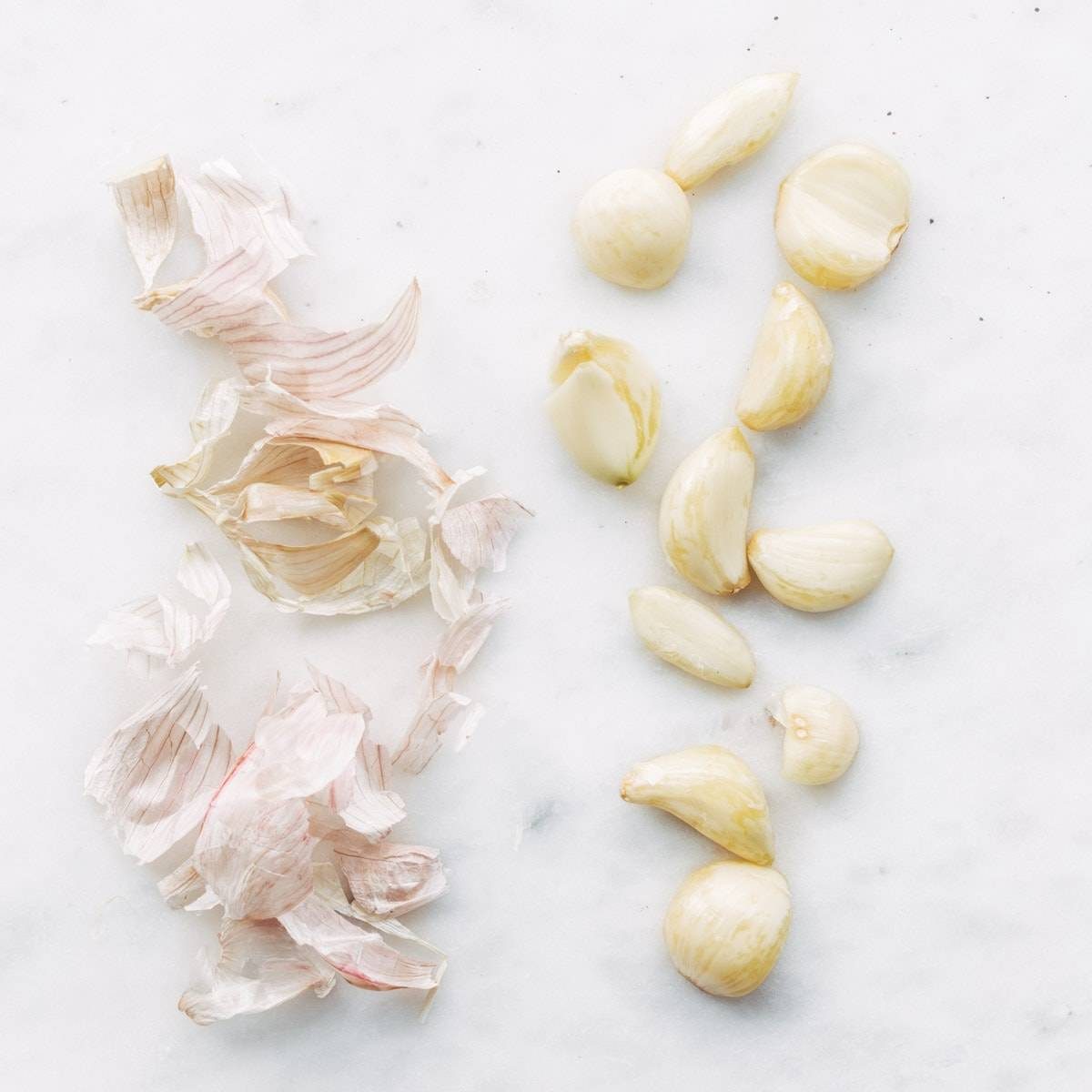 Cloves of peeled garlic on a surface.