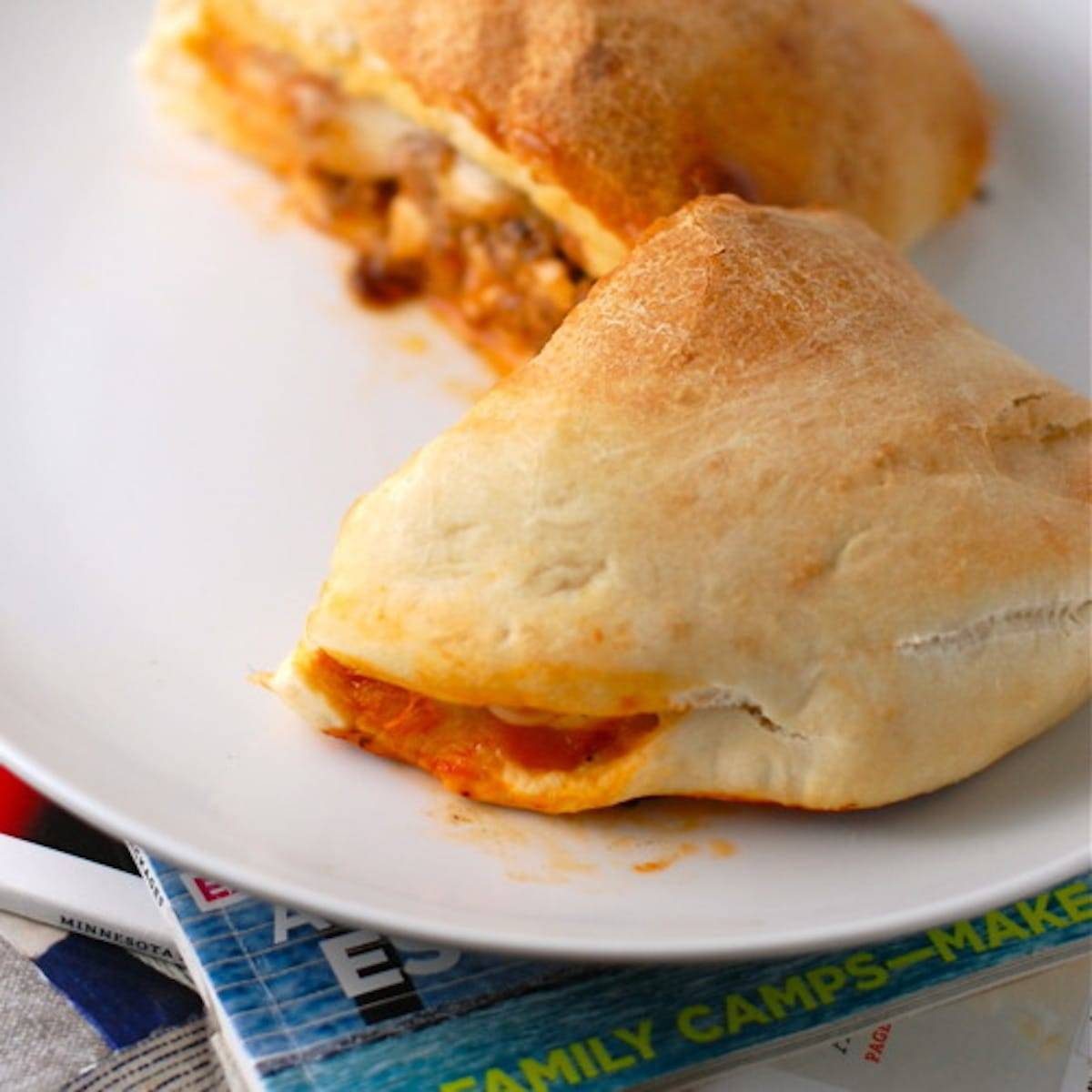 Sausage and mozzarella calzones on a white plate.